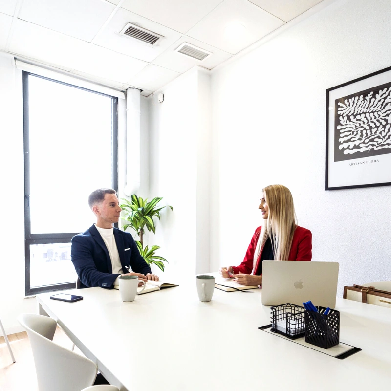 Coach Anna having a leadership coaching session with a male client in an office setting.